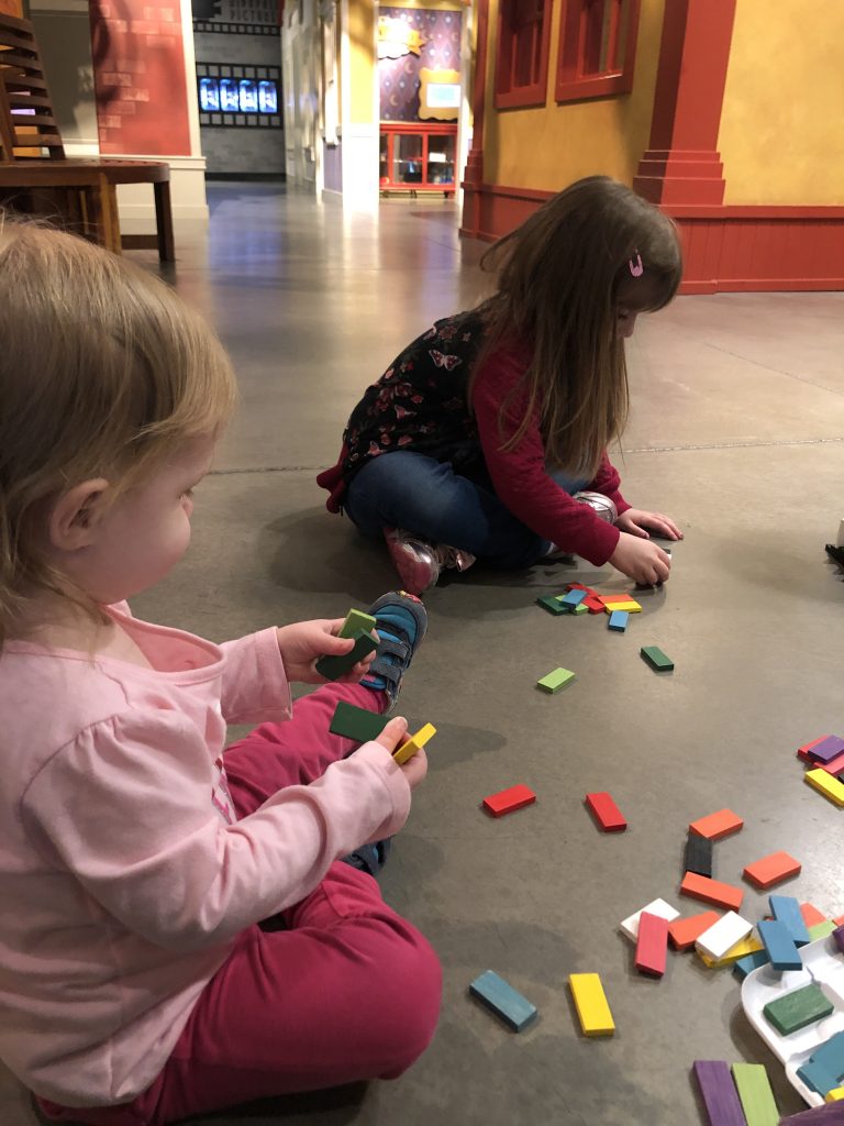 My girls playing dominos for the first time at a local children's museum.